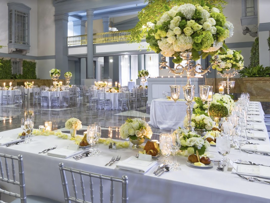 White ballroom reception with tall floral centerpieces and chiavari chairs