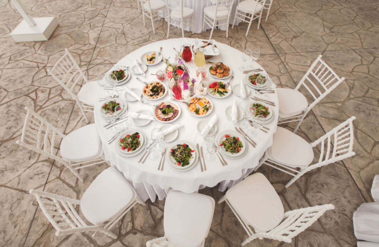 Round white banquet table set with white chiavari chairs, viewed from above